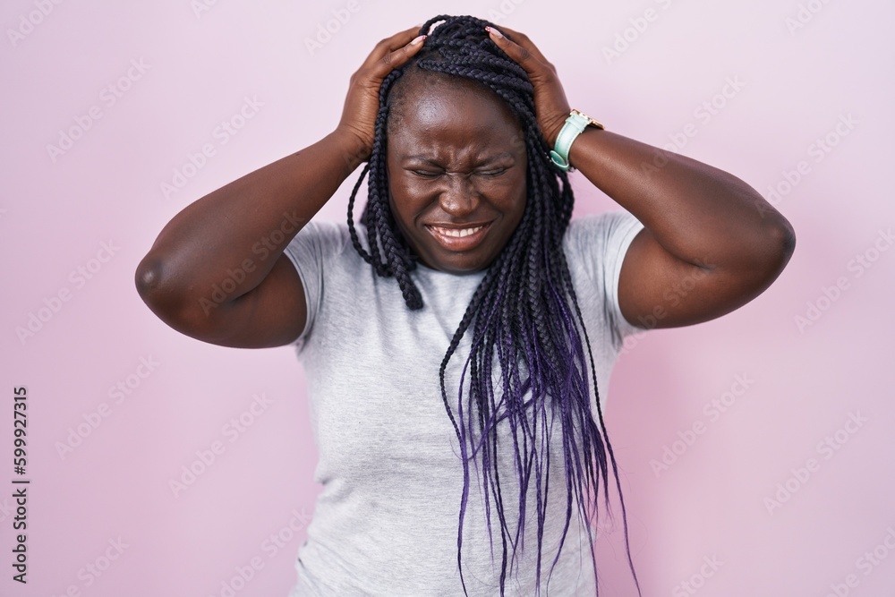 Young african woman standing over pink background suffering from headache desperate and stressed because pain and migraine. hands on head. Young african woman standing over pink background suffering from headache desperate and stressed because pain and migraine. hands on head.