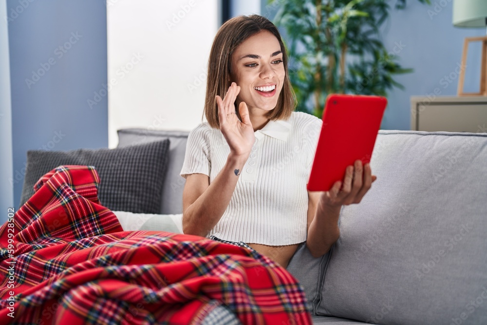 Young beautiful hispanic woman having video call sitting on sofa at home Young beautiful hispanic woman having video call sitting on sofa at home