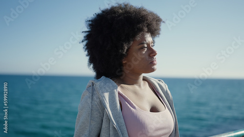 African american woman standing with serious expression at seaside