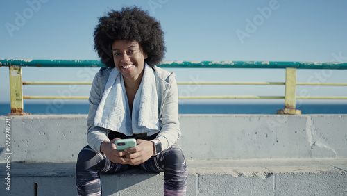African american woman wearing sportswear using smartphone at seaside © Krakenimages.com