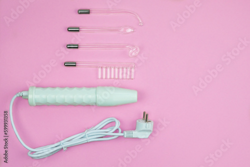 Darsonval for body and hair care on a pink background. Therapy for skin. Darsonvalization. Top view. Copy space. photo