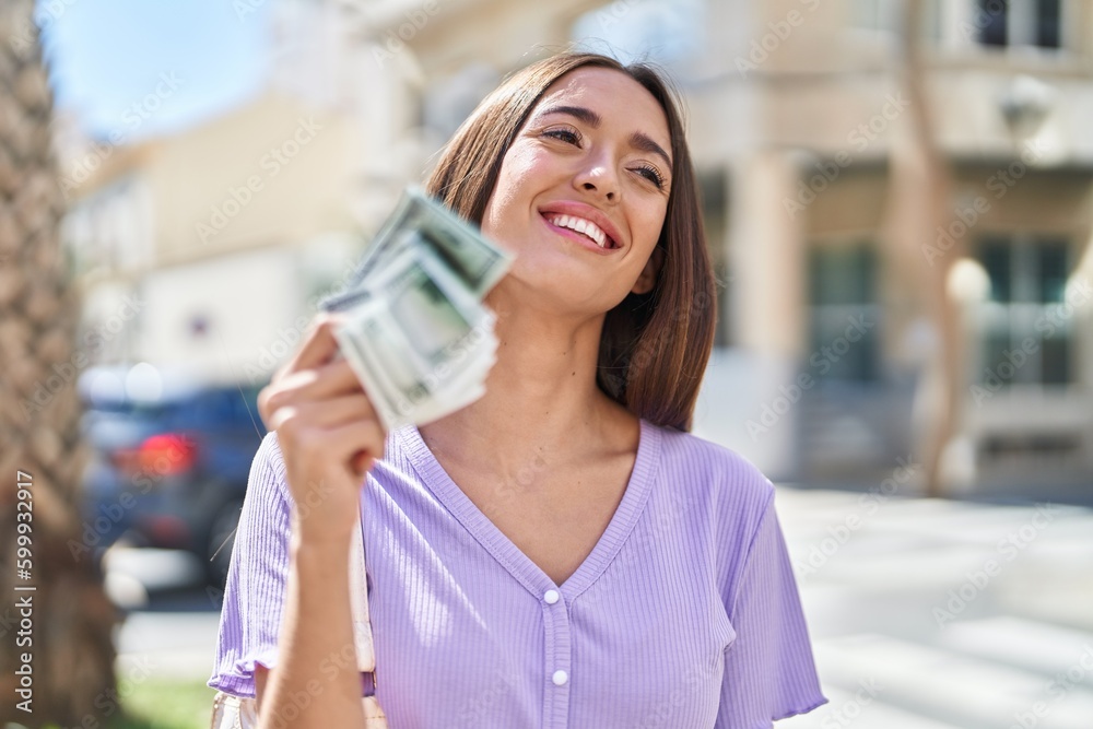 Young beautiful hispanic woman smiling confident holding dollars at street Young beautiful hispanic woman smiling confident holding dollars at street