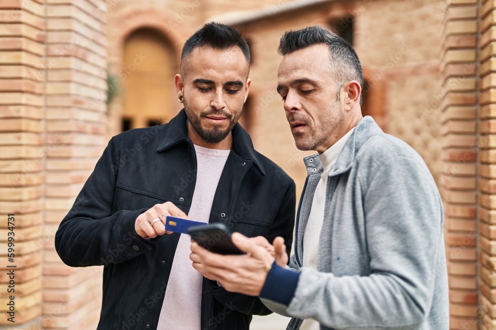 Two men couple using smartphone with relaxed expression at street Two men couple using smartphone with relaxed expression at street