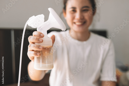 Mom using breast pump machine to pumping milk for her son in bedroom. Colostrum milk, Transitional milk, Breast Pumping milk concept.