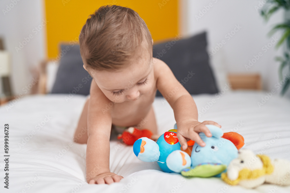 Adorable caucasian baby playing with elephant toy sitting on bed at bedroom Adorable caucasian baby playing with elephant toy sitting on bed at bedroom