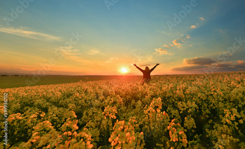 Happy woman on a flower field at sunrise 