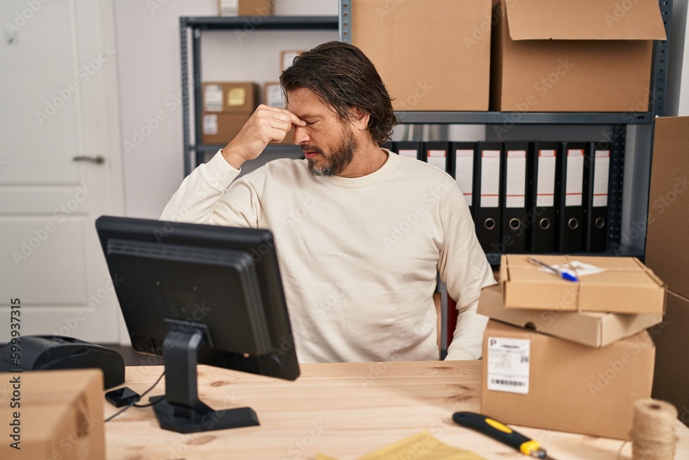 Handsome middle age man working at small business ecommerce tired rubbing nose and eyes feeling fatigue and headache. stress and frustration concept. Handsome middle age man working at small business ecommerce tired rubbing nose and eyes feeling fatigue and headache. stress and frustration concept.