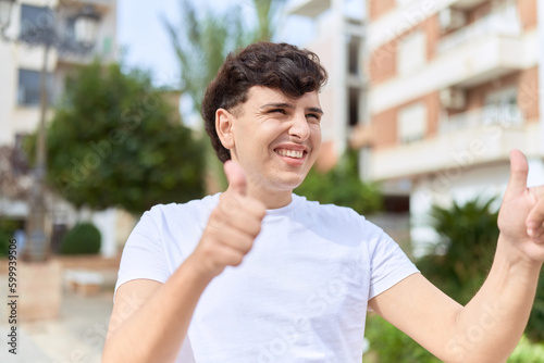 Non binary man smiling confident doing ok sign with thumbs up at park