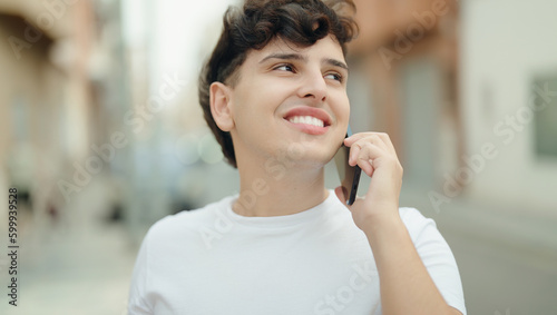 Non binary man smiling confident talking on smartphone at street