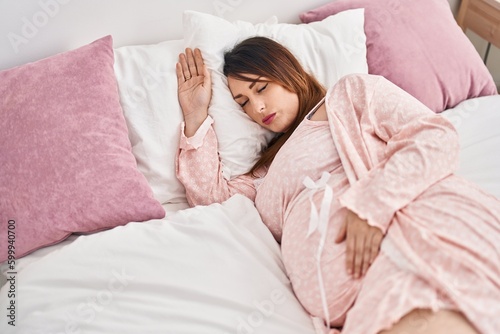 Young pregnant woman lying on bed sleeping at bedroom