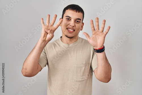 Young arab man wearing casual t shirt showing and pointing up with fingers number nine while smiling confident and happy.