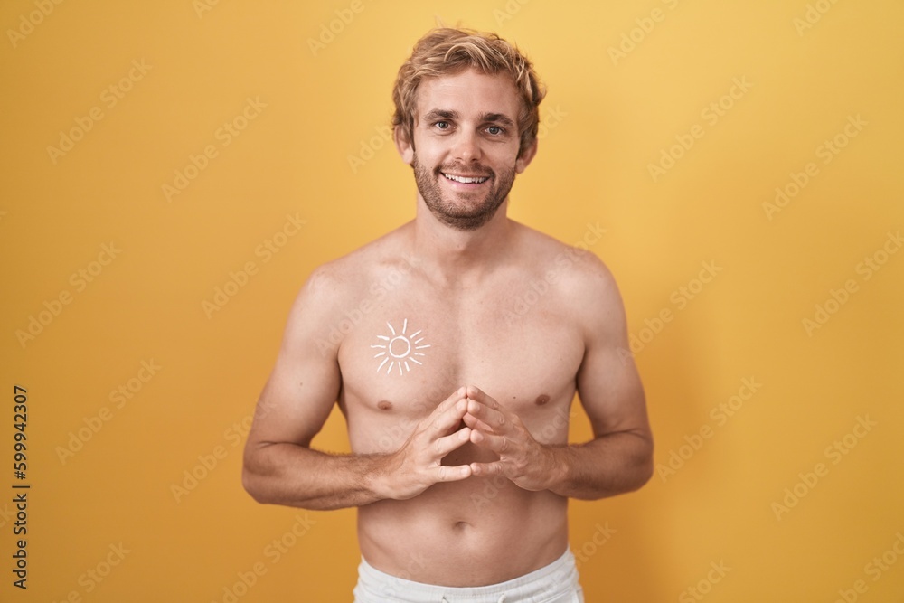 Caucasian man standing shirtless wearing sun screen hands together and fingers crossed smiling relaxed and cheerful. success and optimistic