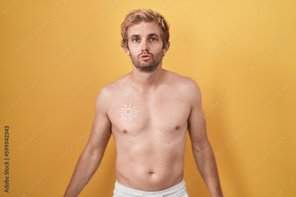 Fototapeta premium Caucasian man standing shirtless wearing sun screen looking at the camera blowing a kiss on air being lovely and sexy. love expression.