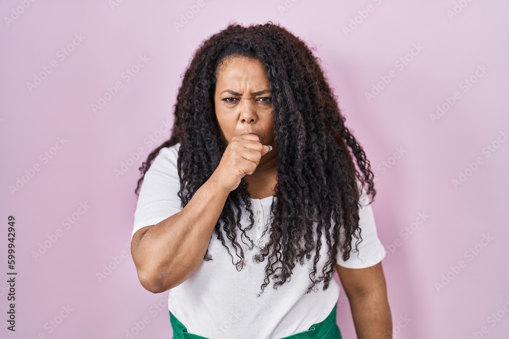 Plus size hispanic woman standing over pink background feeling unwell and coughing as symptom for cold or bronchitis. health care concept.