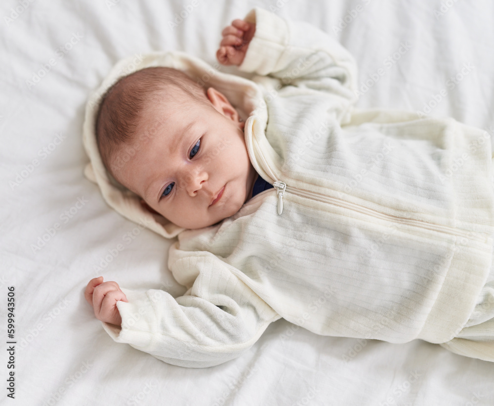 Adorable caucasian baby lying on bed with relaxed expression at bedroom Adorable caucasian baby lying on bed with relaxed expression at bedroom