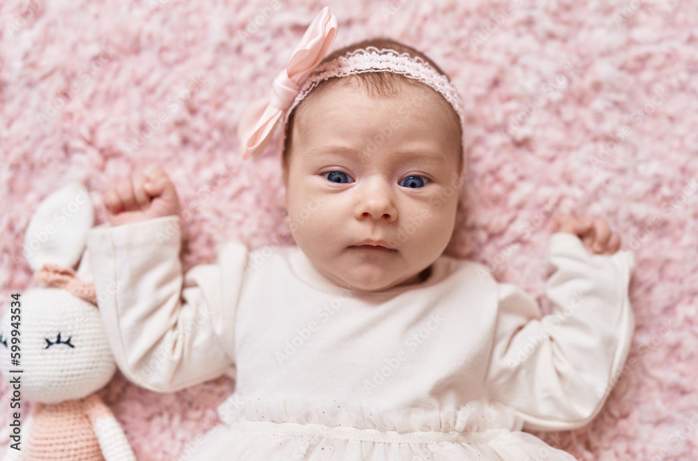 Adorable caucasian baby lying on bed with doll at bedroom Adorable caucasian baby lying on bed with doll at bedroom