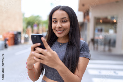 Young arab woman smiling confident using smartphone at street