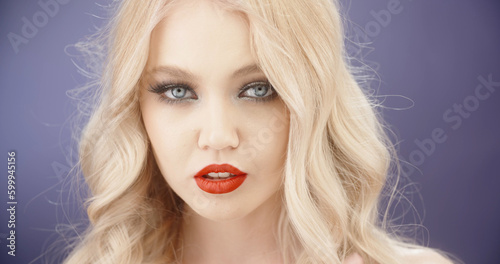 Sensual blonde caucasian girl with bright makeup looking at camera with seductive stare - close up shot 