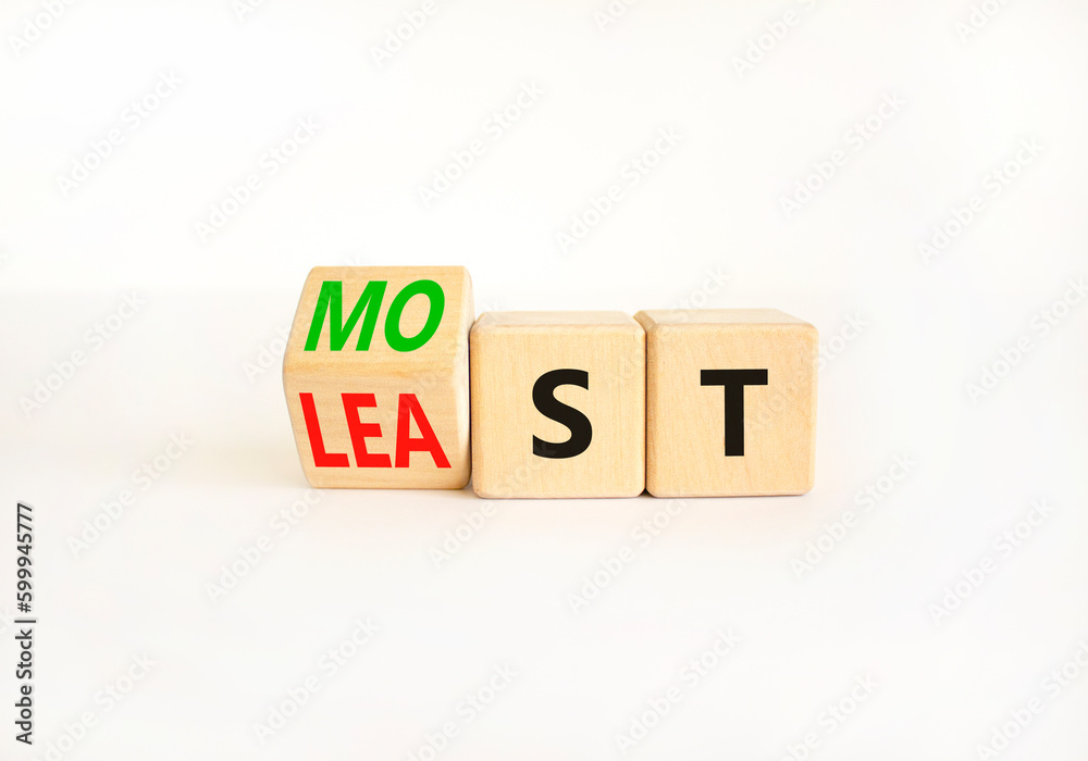 Most or least symbol. Businessman turns wooden cubes and changes the word Least to Most. Beautiful white table white background. Copy space. Business and most or least concept. Most or least symbol. Businessman turns wooden cubes and changes the word Least to Most. Beautiful white table white background. Copy space. Business and most or least concept.
