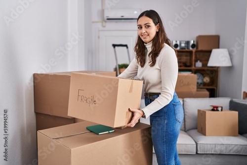 Young beautiful hispanic woman smiling confident holding fragile package at new home © Krakenimages.com