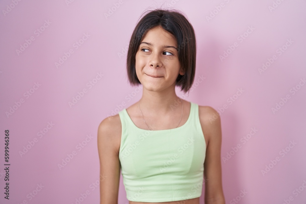 Young girl standing over pink background smiling looking to the side and staring away thinking. Young girl standing over pink background smiling looking to the side and staring away thinking.