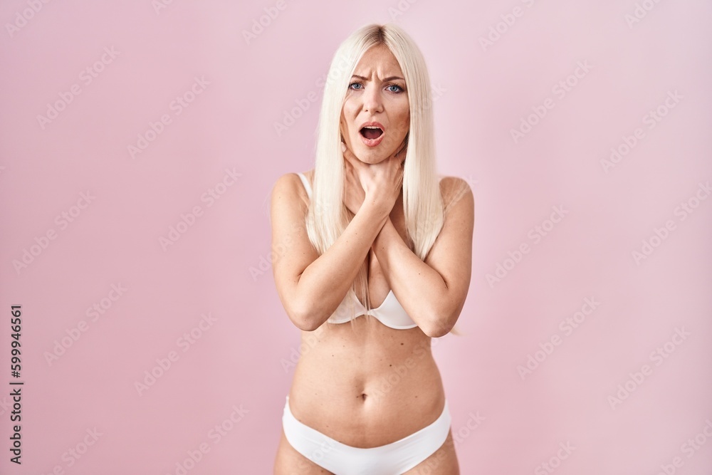 Caucasian woman wearing lingerie over pink background shouting and suffocate because painful strangle. health problem. asphyxiate and suicide concept.