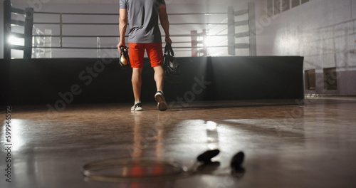 An athlete walking into a gym with a bag and boxing gloves  ready to start training - sports  fitness  martial arts concept 