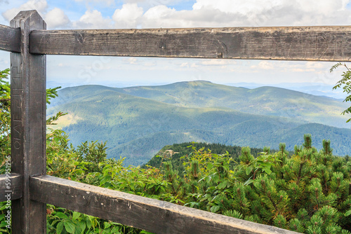 Panorama of the Beskid Żywiecki peaks (Poland) seen through a wooden fence from the observation deck on Sokolica on the way to Babia Góra from the Krowiarki pass on a dramatically cloudy summer day.