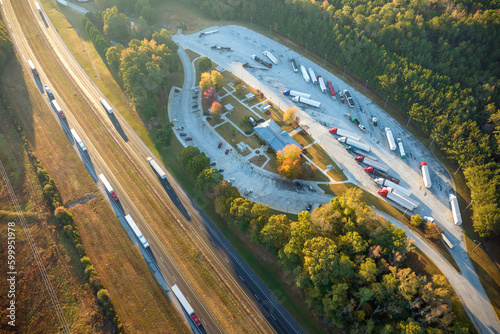 View from above of big parking rest area for cars and trucks near busy american highway with fast moving traffic. Recreational place during interstate travel