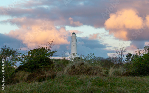 A white lighthouse in front of orange sunrise clouds at the European Wadden island 'Schiermonnikoog' in Friesland, Holland