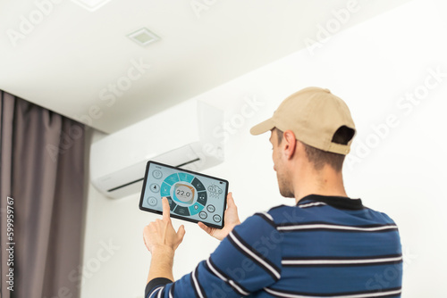 Installation service repair maintenance of an air conditioner, by cryogenist technican worker evacuate the system with tablet in blue shirt and baseball cap photo
