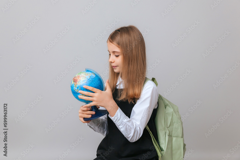 Caucasian young teenager schoolgirl student holding a globe on a gray background, isolated. Happy earth day Caucasian young teenager schoolgirl student holding a globe on a gray background, isolated. Happy earth day