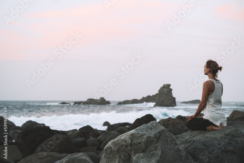 Woman is practicing yoga, meditating on the beach.