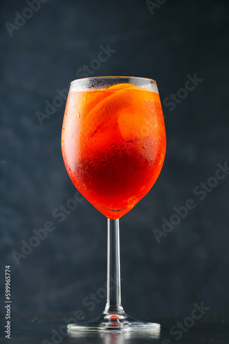 Aperol Spritz cocktail on dark background. Cocktail Aperol Spritz with oranges and ice cubes in glass. Summer refreshing drink