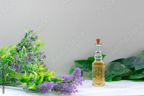 Essential oil bottle, flowers in front and leaves in the background. Aromatherapy, natural remedies