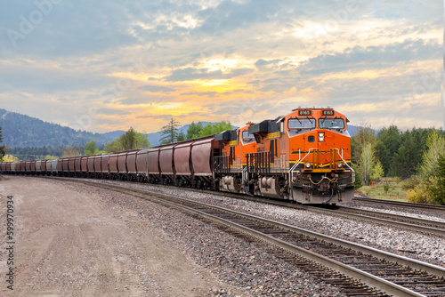 Canvas Print freight train with a colorful sunset in background near Whitefish, Montana