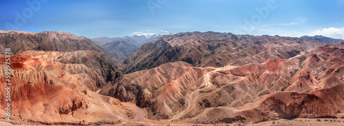 Large panoramic aerial view captures the raw beauty of rugged red mountains stretching endlessly towards the horizon in Kyrgyzstan
