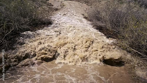 Warm spring weather melts high mountain snow pack sending muddy runoff water splashes violently-Slow motion photo