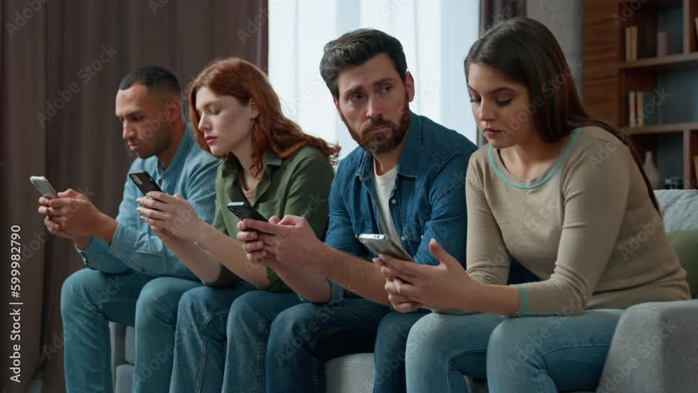 Sad man look at friends mobile phone addicted multiracial people lost in gadgets overuse social media networks chatting online diverse boring women men sit in row at home ignoring smartphone addiction