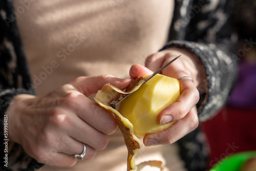 Close up of women holding and peeling potato with a knife photo