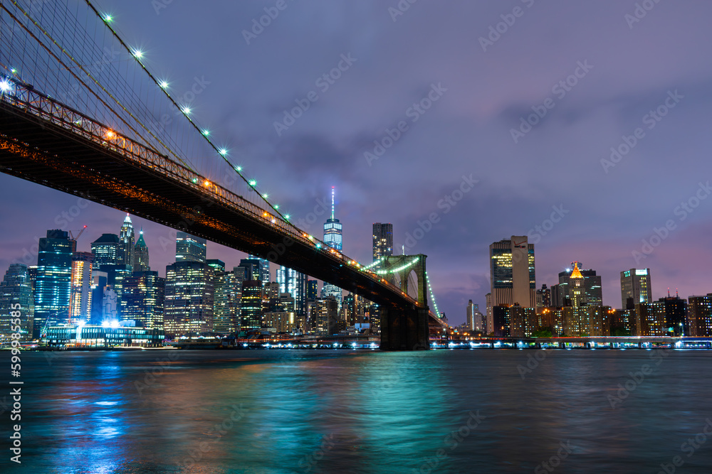 Skyline of downtown New York City Brooklyn Bridge and skyscrapers over East River illuminated with lights at dusk after sunset view from Brooklyn	