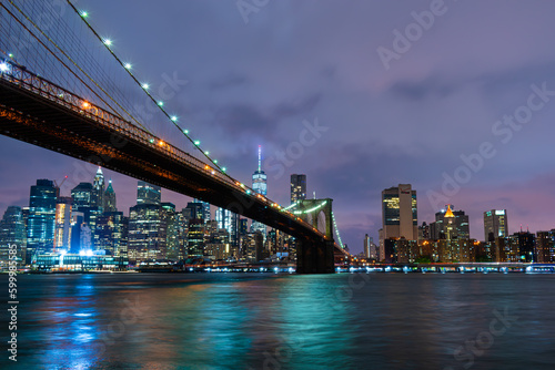 Fototapeta Naklejka Na Ścianę i Meble -  Skyline of downtown New York City Brooklyn Bridge and skyscrapers over East River illuminated with lights at dusk after sunset view from Brooklyn	