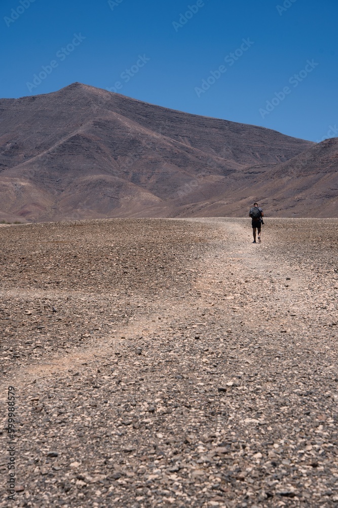 Adventure travel. Brave man walking through an arid landscape on a sunny day. 