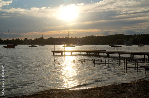 sunlit, romantic lake Ammersee with its long piers and sailing boats on a sunny evening in Herrsching, Germany © Julia