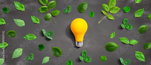 Yellow light bulb with green leaves - Flat lay