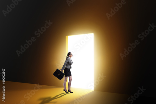 Businesswoman entering backlit door in escape concept