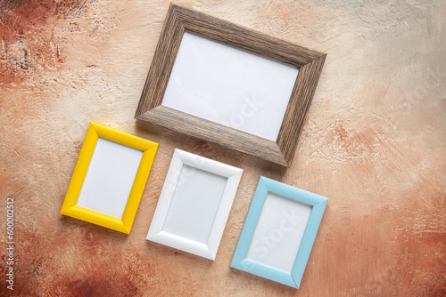 Top view of four wooden photo frames in different sizes hung on side by side on mix color wall with free space
