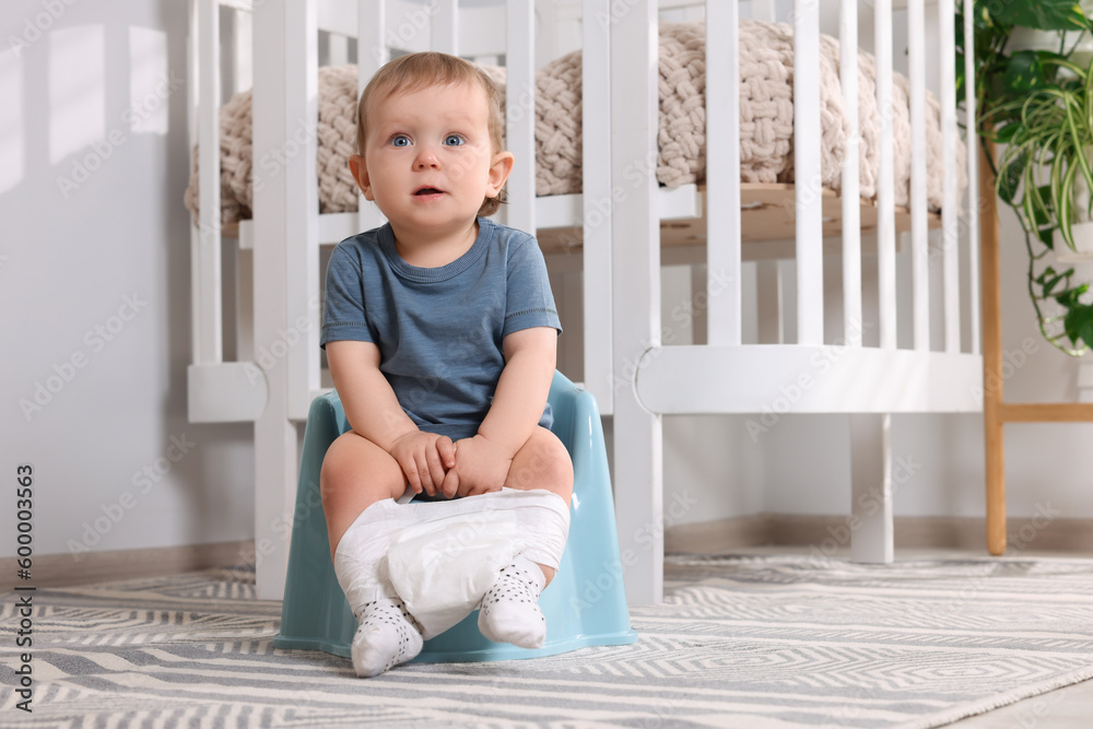 Little child sitting on plastic baby potty indoors. Space for text Little child sitting on plastic baby potty indoors. Space for text