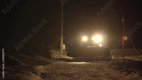 Emergency saving expedition of lost mountaineers at night. Snowcat ratrac tractor drive fast rescuing lost people in dark evening. photo