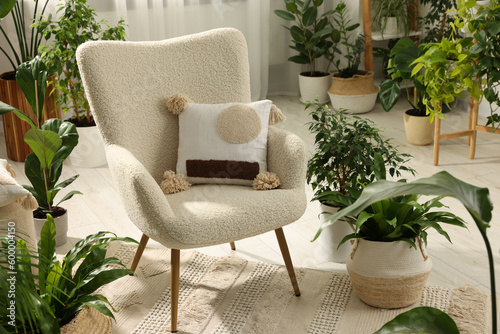 Relaxing atmosphere. Many different potted houseplants around stylish armchair in room